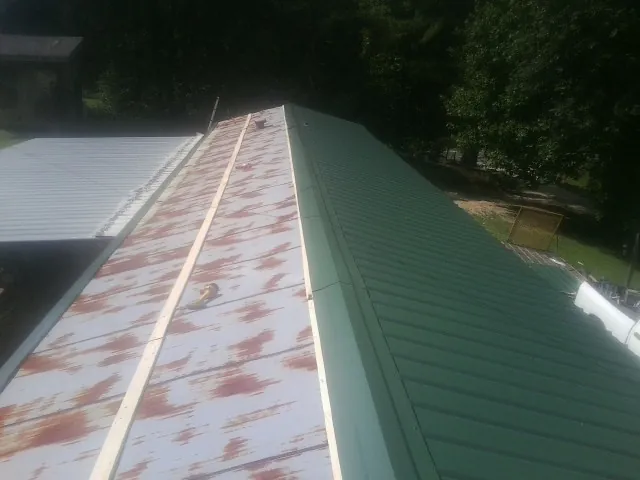 Old rusted panels beside newly installed green metal roofing — Wind Damage Roof Repair by Roofing Brothers in North Lewisburg