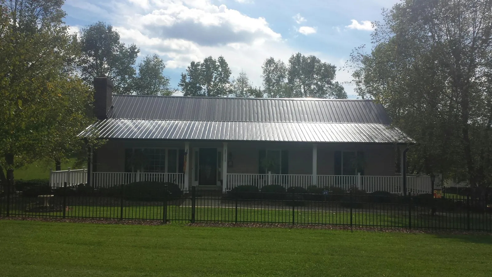 Gray metal roof on a brick ranch with a full width front porch — Gutter Guard Installation work by our crew in North Lewisburg