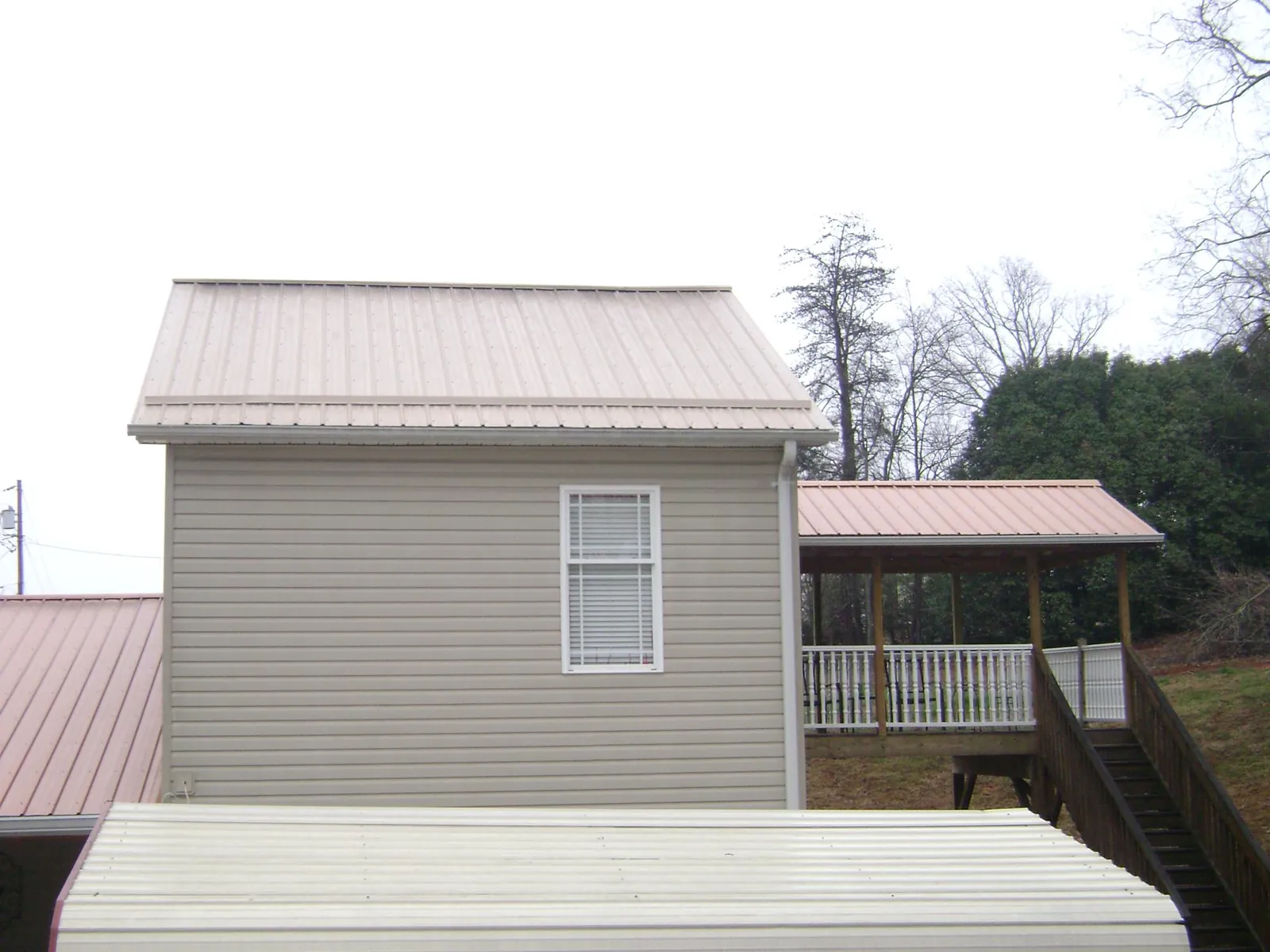 Tan metal roofs on a two story addition and attached porch, from a Roof Replacement job in North Lewisburg