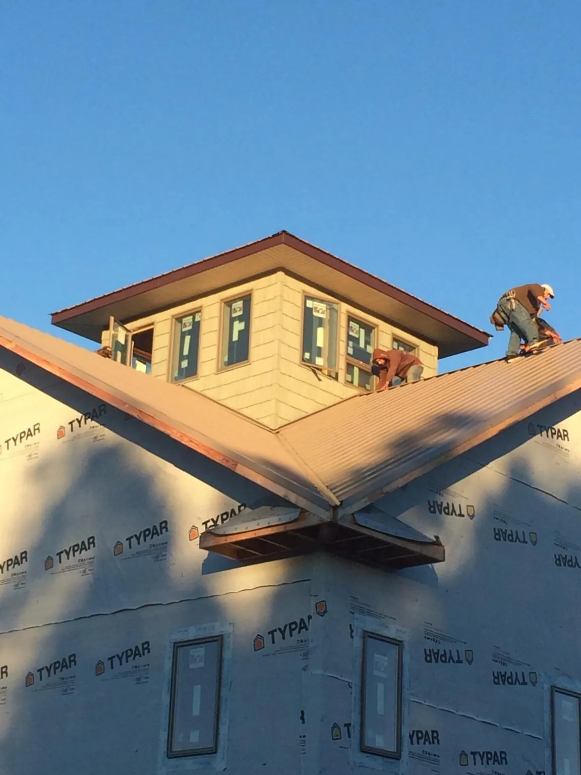 Roofers working around a rooftop cupola on a new metal roof at sunset — Roof Waterproofing in North Lewisburg by Roofing Brothers